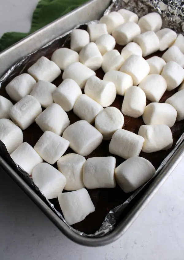 pan of half cooked s'mores bars with bright white marshmallows on top.