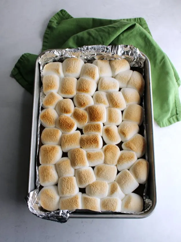 Pan of freshly baked s'mores bars with golden brown toasted marshmallows on top.
