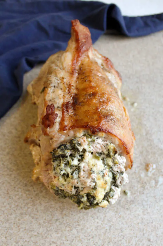 spinach and cheese stuffed pork loin on cutting board resting