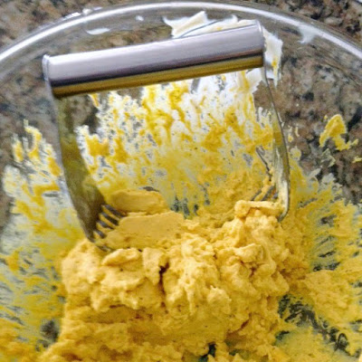 deviled egg filling being mashed with a pastry cutter