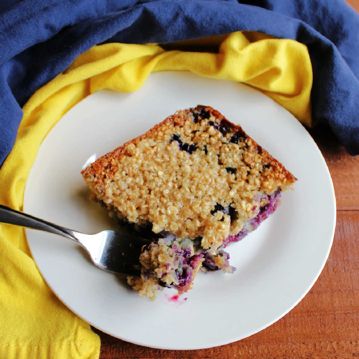 Bite of lemon blueberry baked oatmeal on fork showing soft texture and big blueberries inside, ready to be eaten.