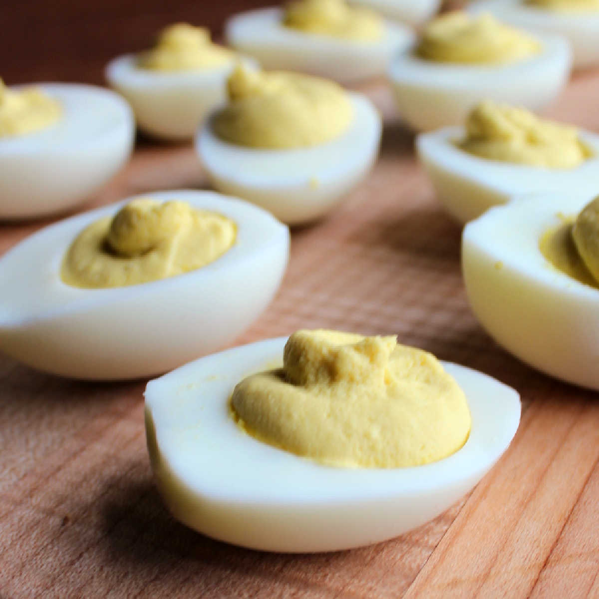 close up of deviled eggs on wood serving board.