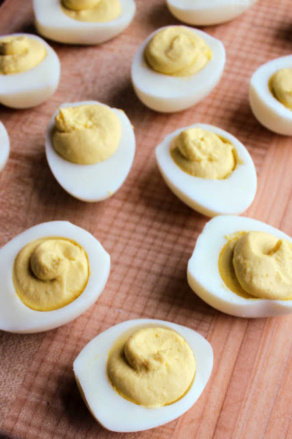 deviled eggs with creamy yolk filling on wooden board