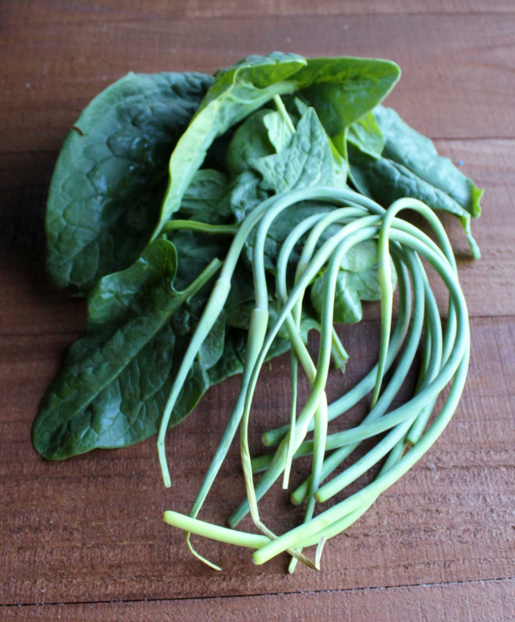 fresh garlic scapes and large leaves of spinach.