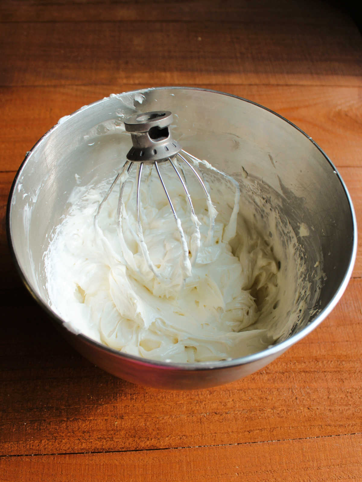 Mixer bowl with whisk and fluffy whipped cream cheese ermine frosting. 