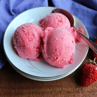 bowl with three scoops of pink strawberry sherbet and spoon