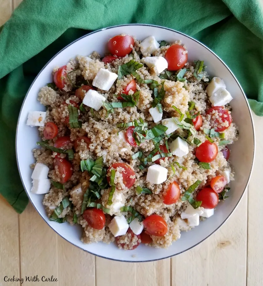 bowl of quinoa salad with tomatoes basil and mozzarella pearls