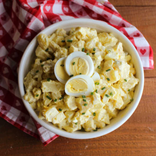 bowl of potato salad with sliced egg and bits of chive on top