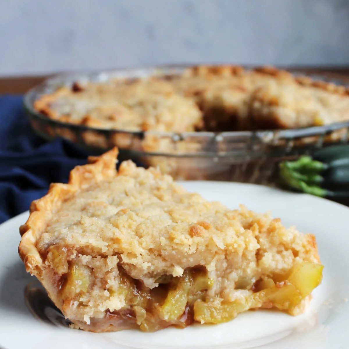 Close slice of mock apple zucchini pie showing cinnamon filling and buttery crumb topping.