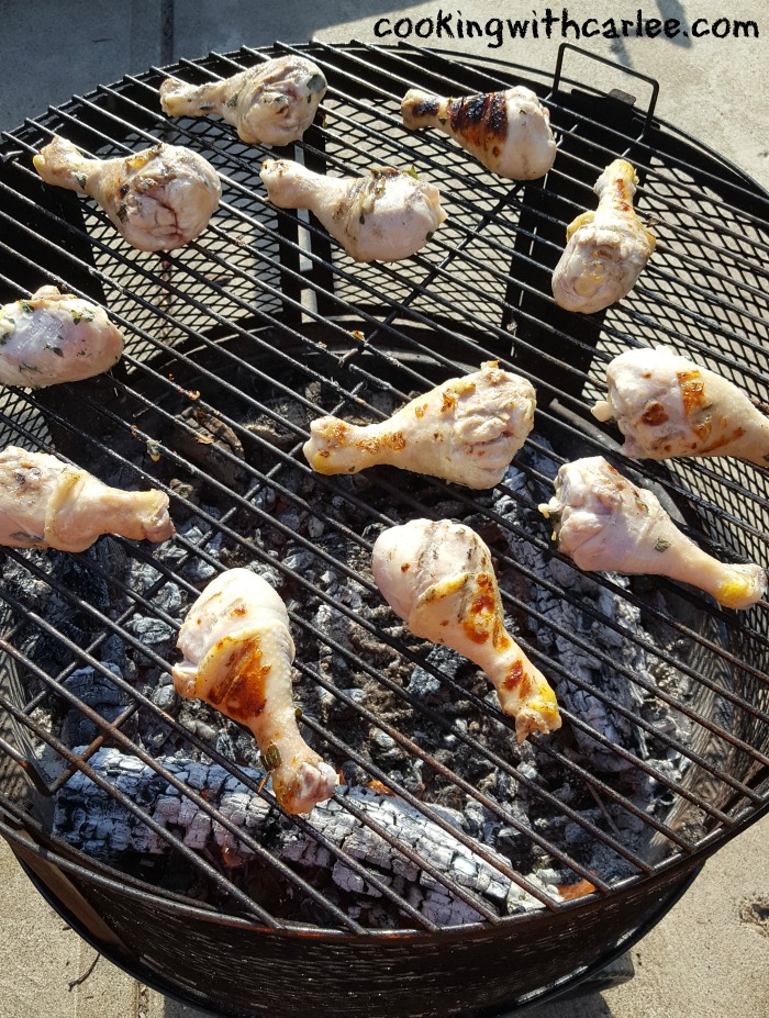 Chicken drumsticks being grilled over wood fire.