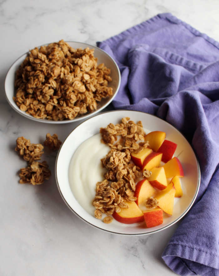 bowl of yogurt with maple cinnamon granola and peaches on top