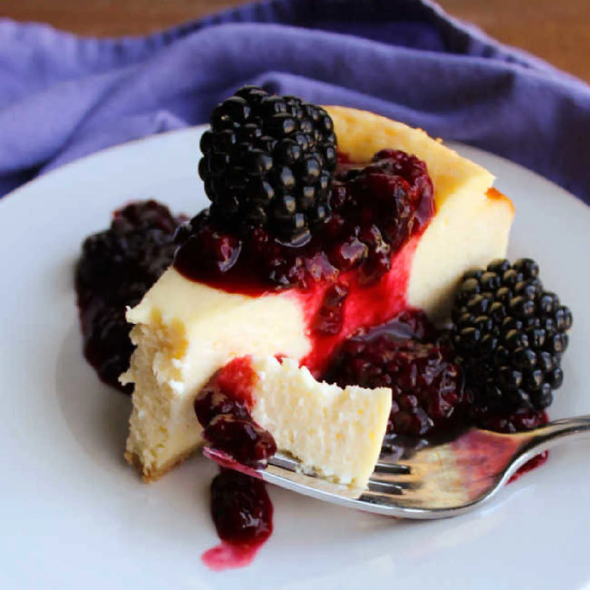 slice of creamy cheesecake with blackberry sauce.