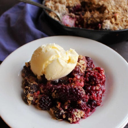 Serving of blackberry crisp with scoop of ice cream on top.