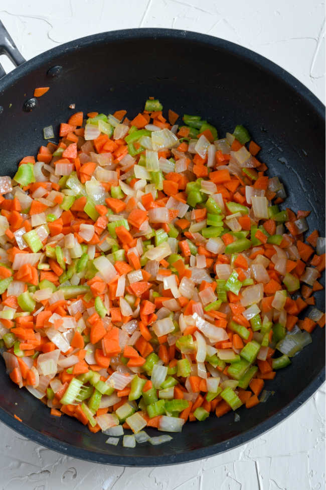 Carrots, onions and celery cooking in pan.