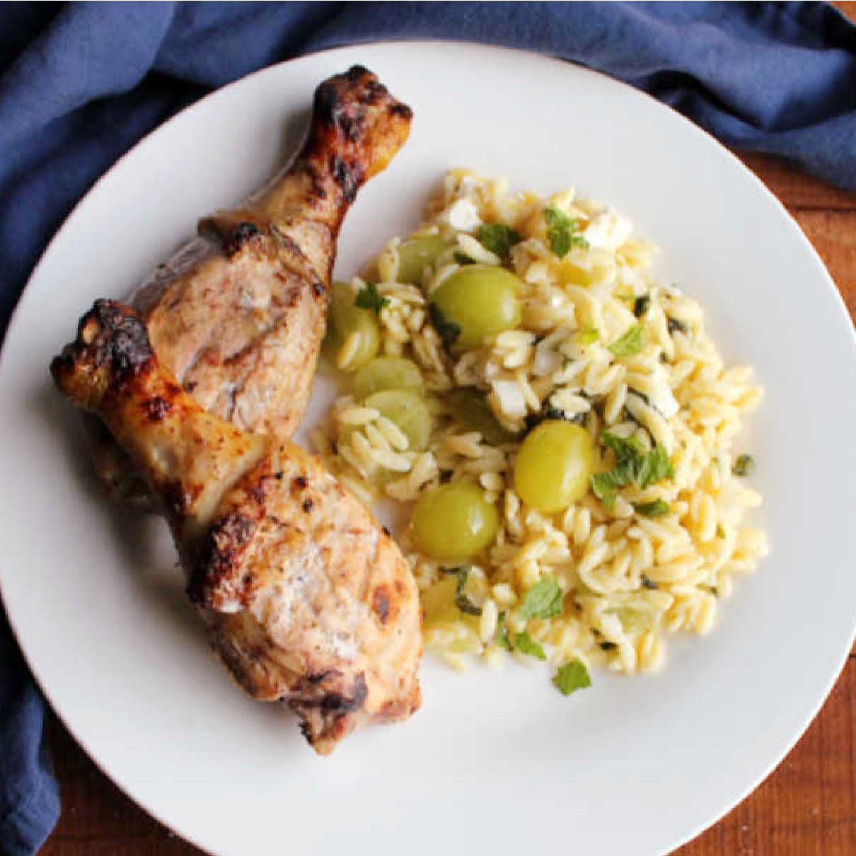 grilled chicken that has been marinated in lemon, yogurt and herbs on plate with orzo pasta salad.
