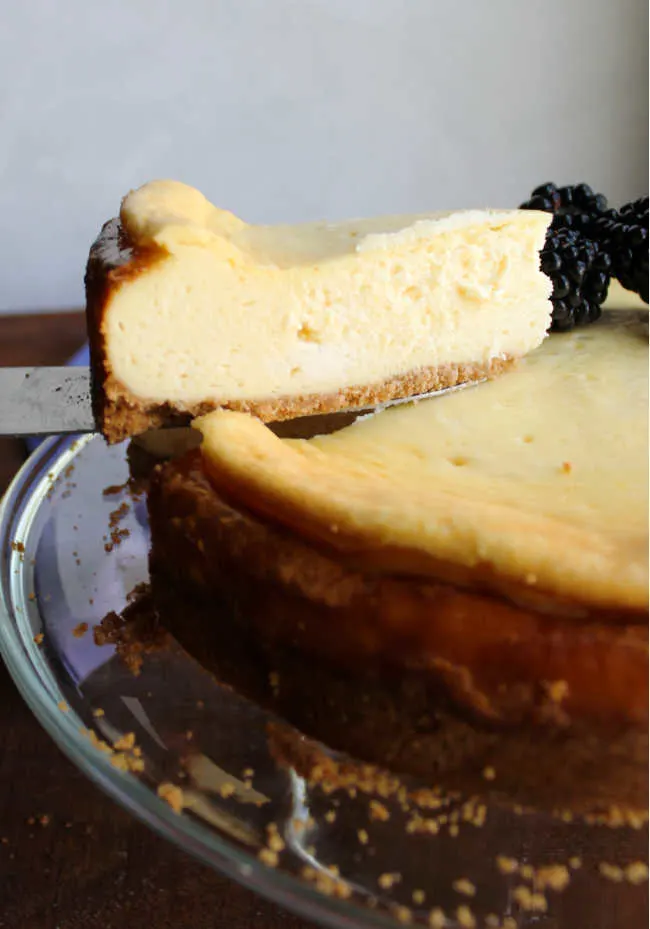 lifting slice of sweetened condensed milk cheesecake out of whole dessert, ready to serve.