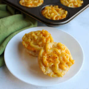 Plate with two baked macaroni and cheese muffins on it.