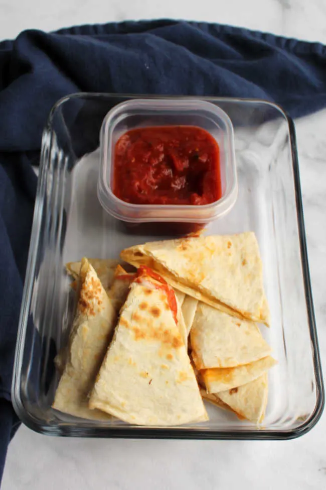 wedges of quesadilla and small container of sauce ready to be packed into lunchbox.