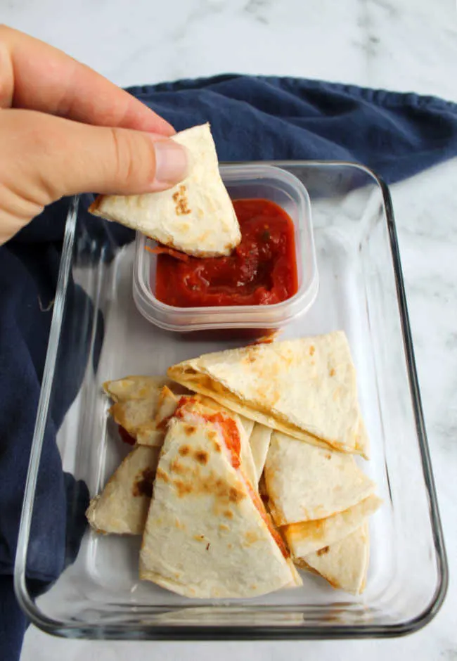 quesadilla wedge dipped in pizza sauce and ready to eat.