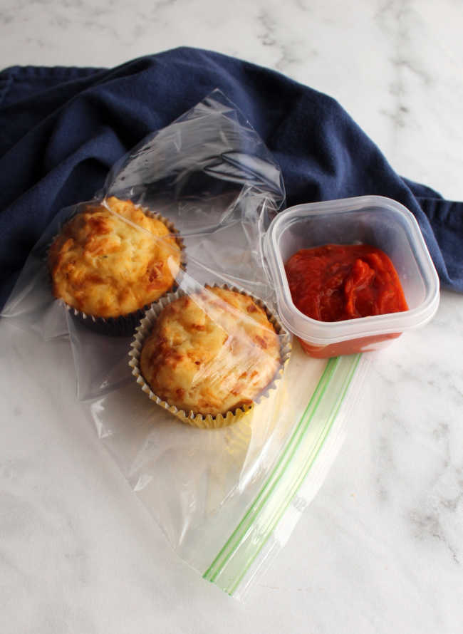 two muffins in plastic bag with small container of pizza sauce