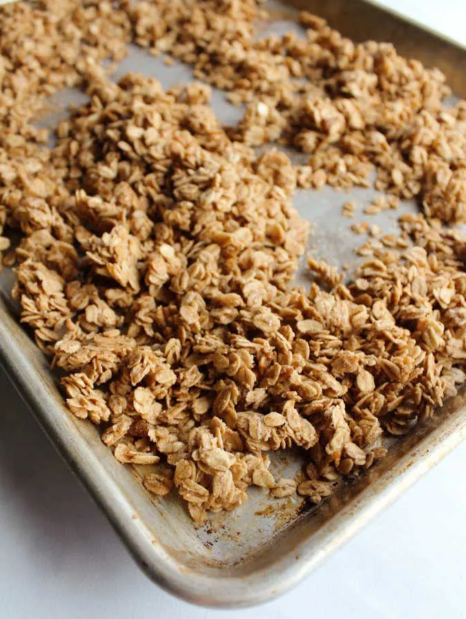 sheet pan of clumps of maple cinnamon granola fresh from the oven.
