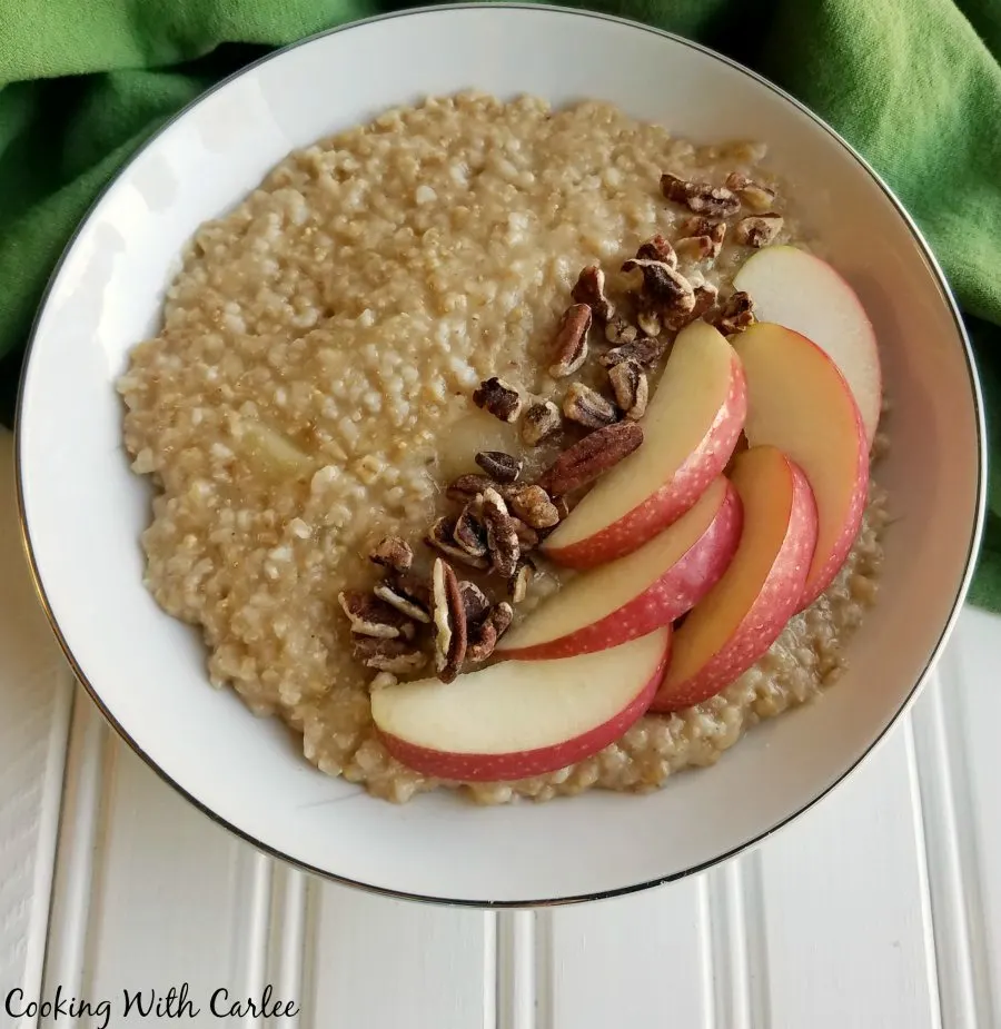 Bowl of apple pie steel cut oats topped with pecans and sliced apples.