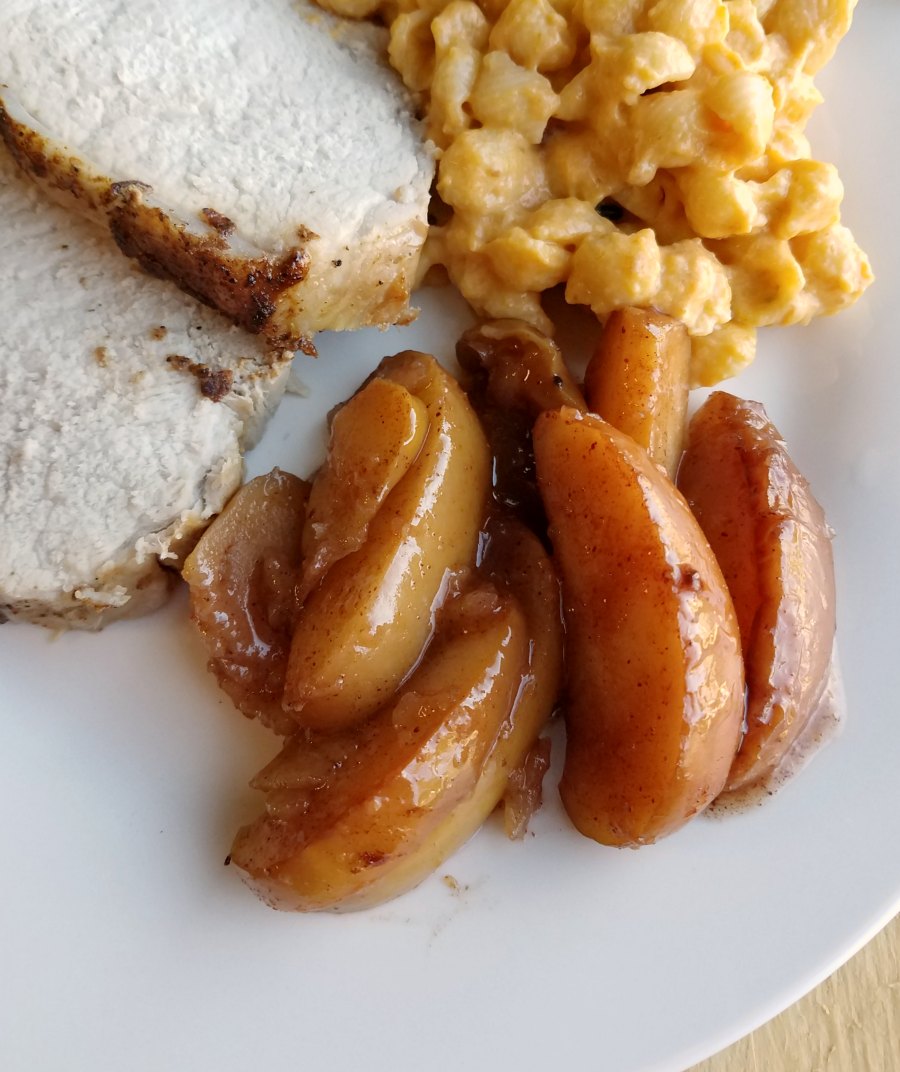Cinnamon apple slices on plate with macaroni and cheese and pork loin.