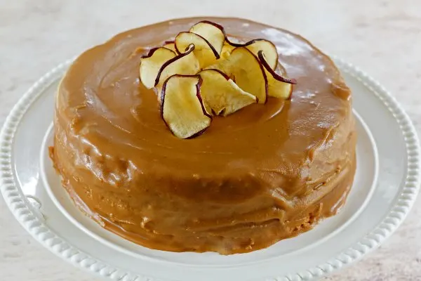 caramel frosted cake with pile of apple chips on top.