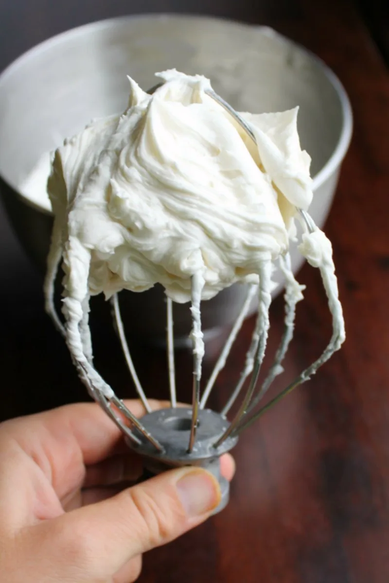 Balloon whisk mixer attachment filled with fluffy white boiled milk frosting. 