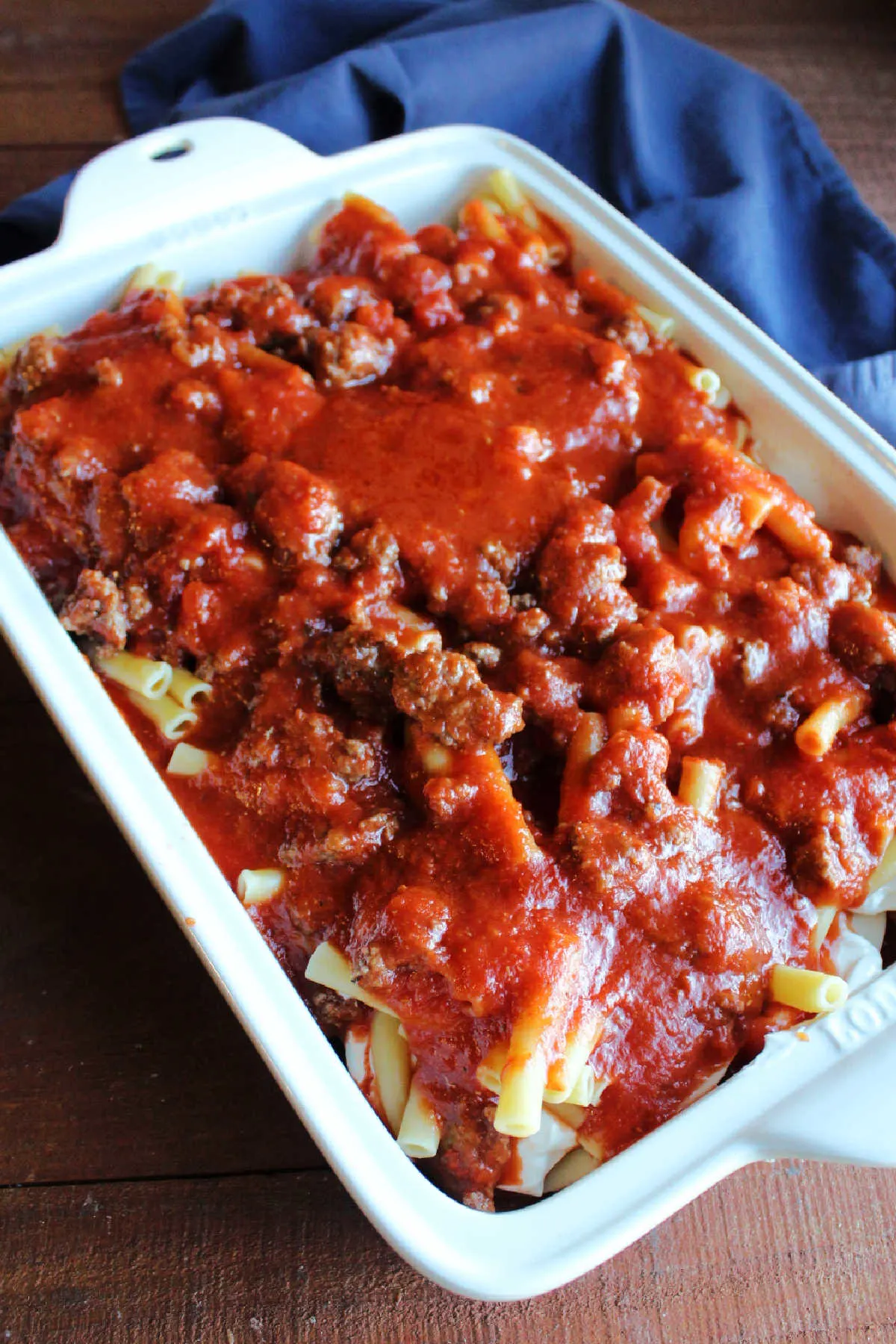 Another layer of pasta and meat sauce on top of cheese and sour cream layer in casserole dish.