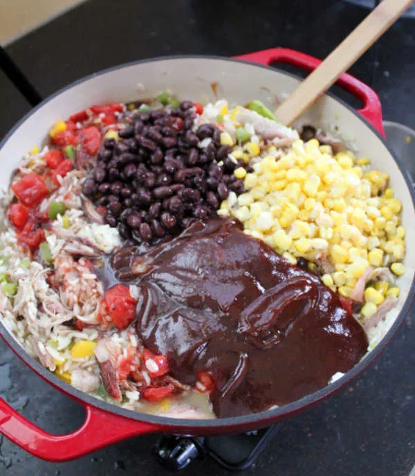 Adding black beans, corn and bbq sauce to skillet with rice and pulled pork mixture. 