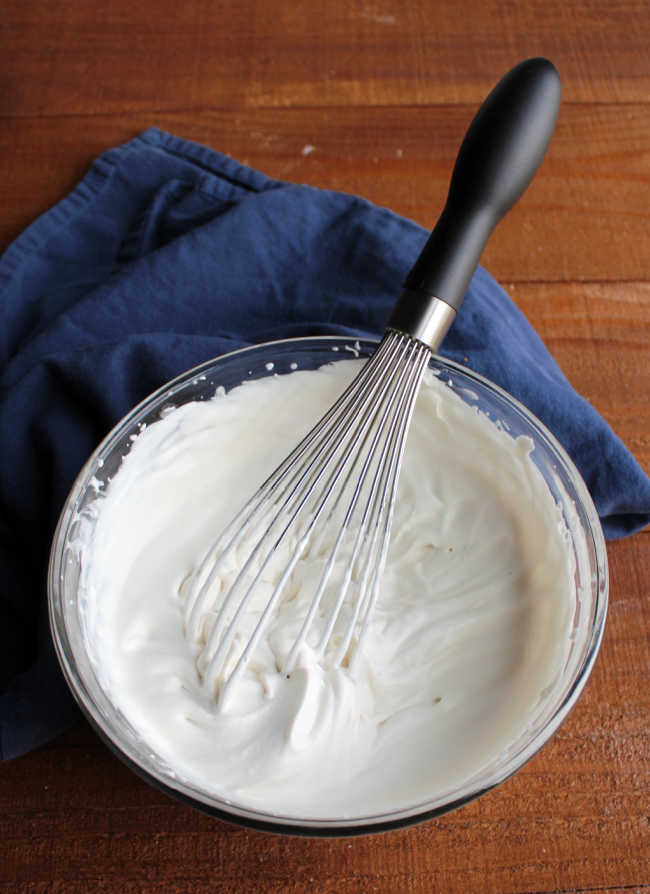 bowl of maple whipped cream with whisk.