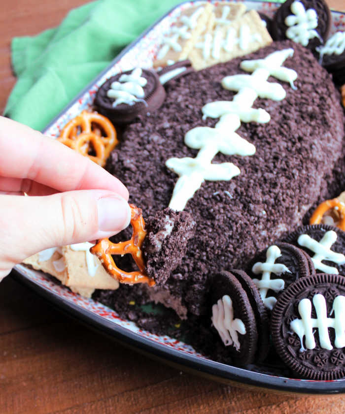 dipping pretzel into football shaped chocolate cheese ball