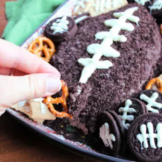 dipping pretzel into football shaped chocolate cheese ball