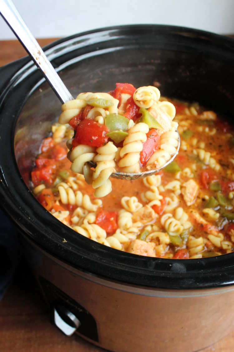 ladle of chicken cacciatore soup being lifted out of slow cooker.