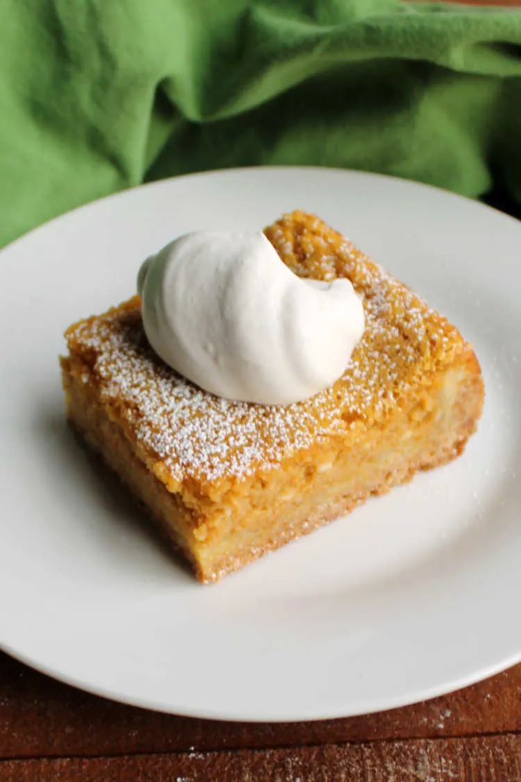slice of pumpkin gooey butter cake with maple whipped cream.