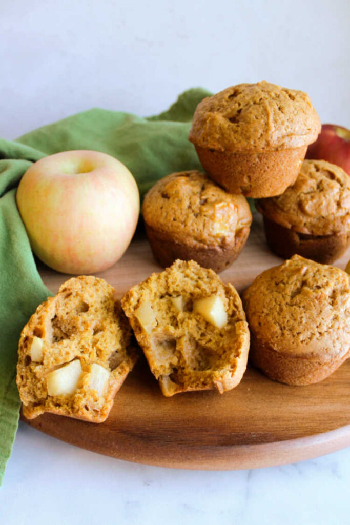 stack of pumpkin muffins with one broken open to show apple chunks inside.