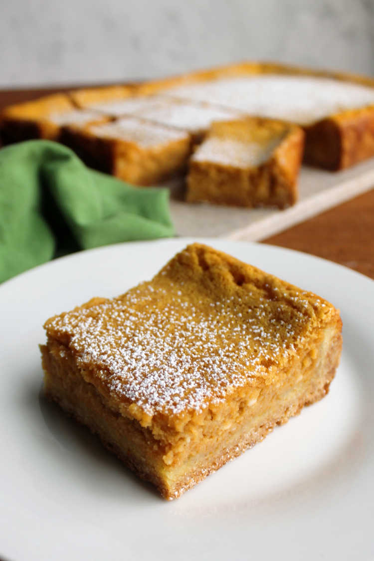 powdered sugar dusted pumpkin gooey butter cake bar on plate ready to eat.