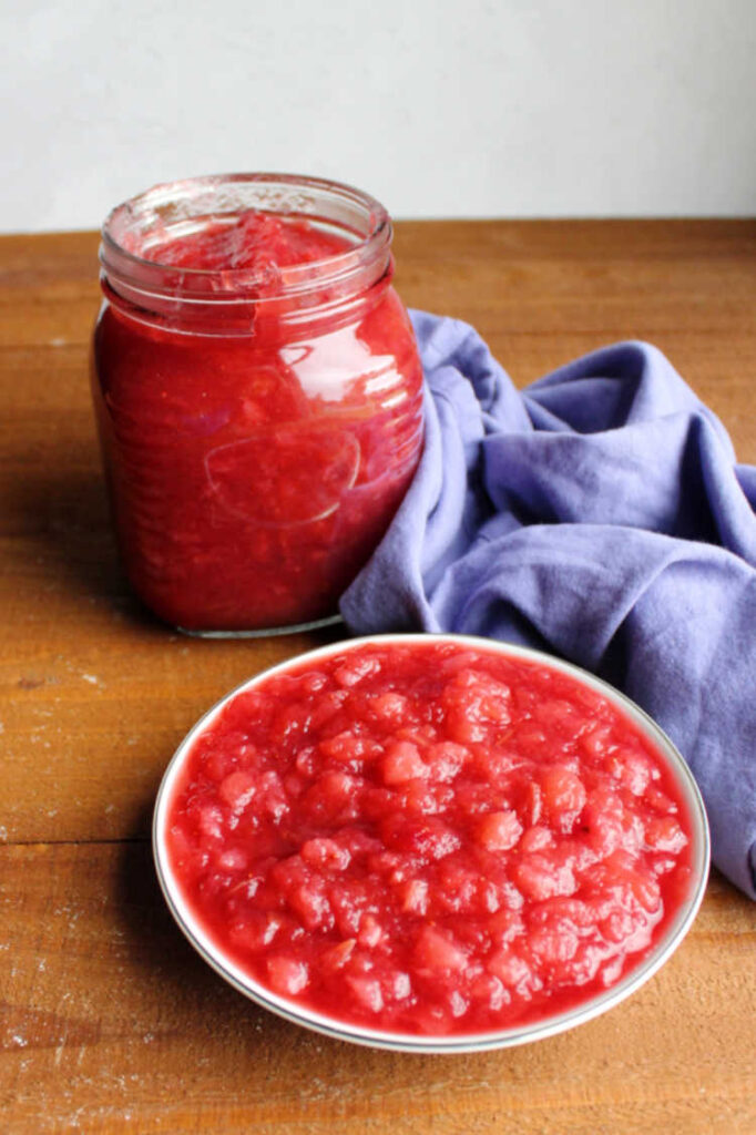 jar of cranberry apple sauce next to serving in bowl.
