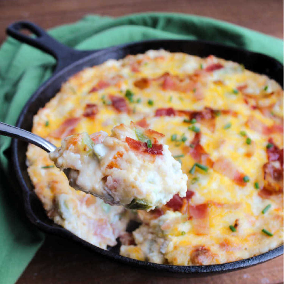 spoonful of melty, gooey, cheesy jalapeno popper dip being lifted out of cast iron pan.