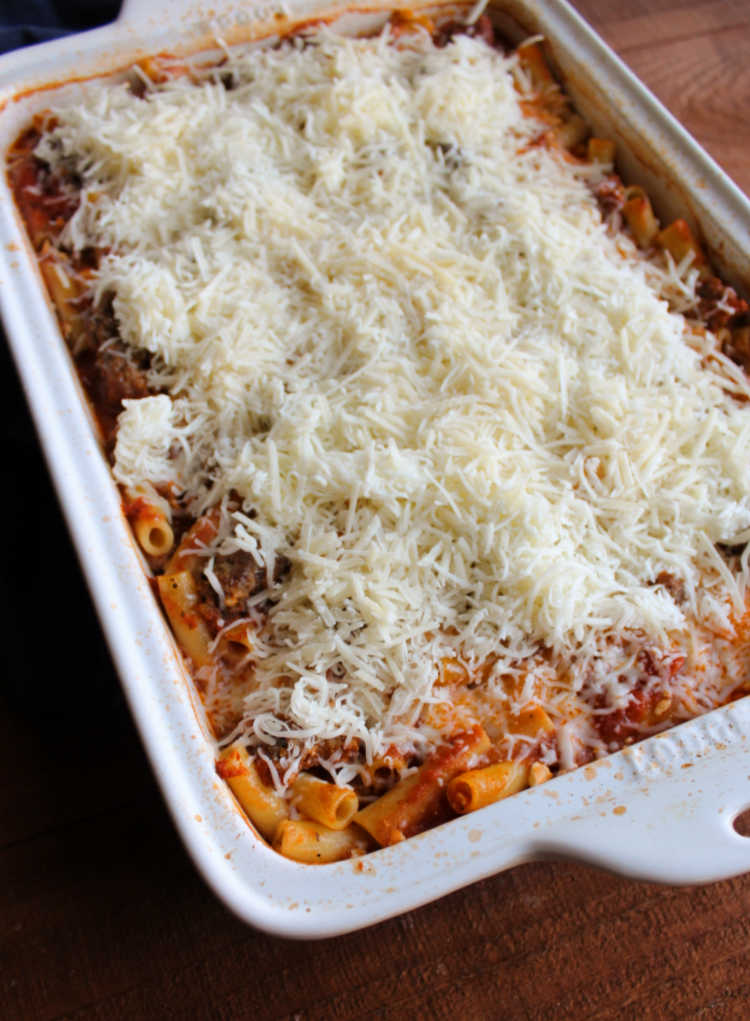 baked ziti topped with shredded cheese ready to go back into the oven.