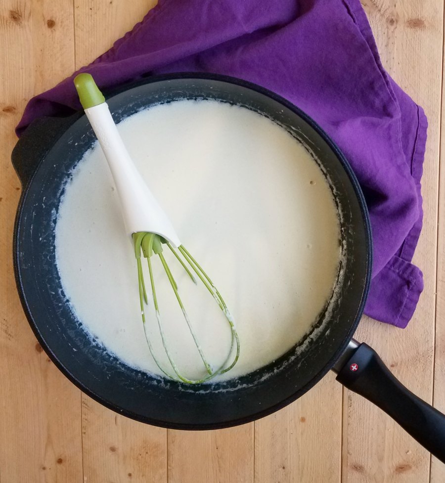 saute pan of alfredo sauce with whisk.