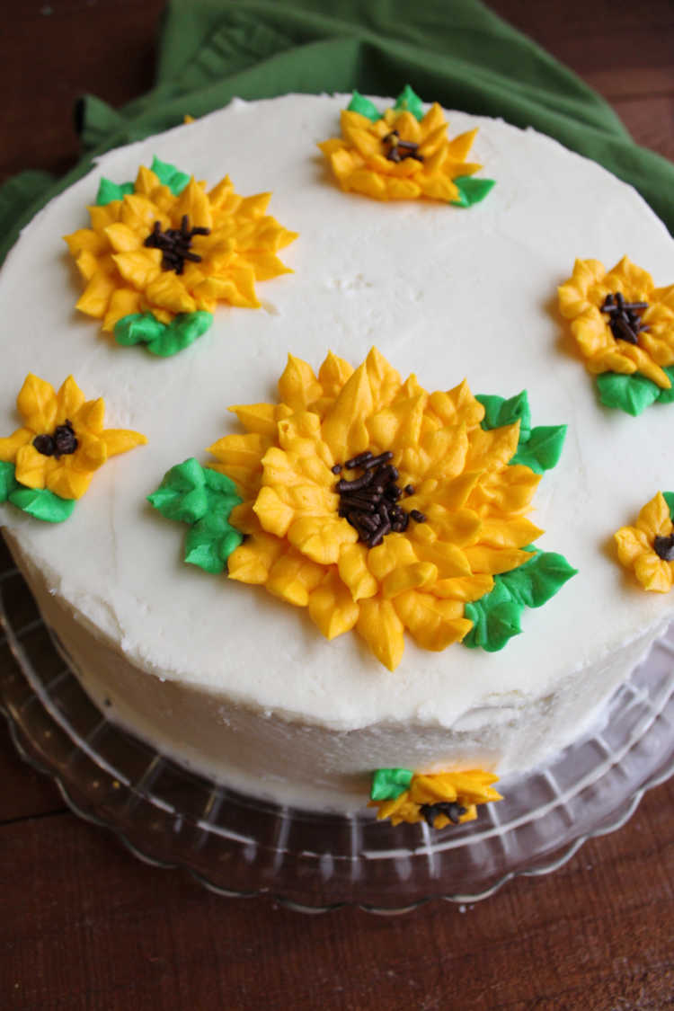 cake frosted in white buttercream with frosting sunflowers piped on top.
