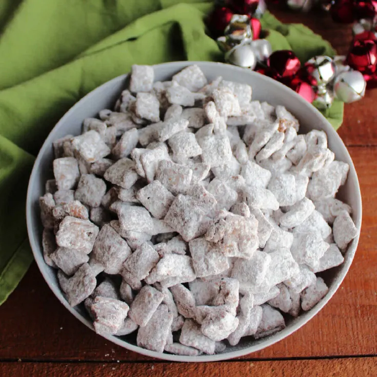 Bowl of original puppy chow with chocolate and peanut butter coated Chex cereal covered with powdered sugar.