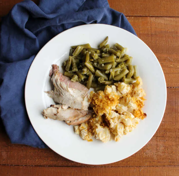 green beans, slices of grilled turkey and cheesy potato casserole on dinner plate.