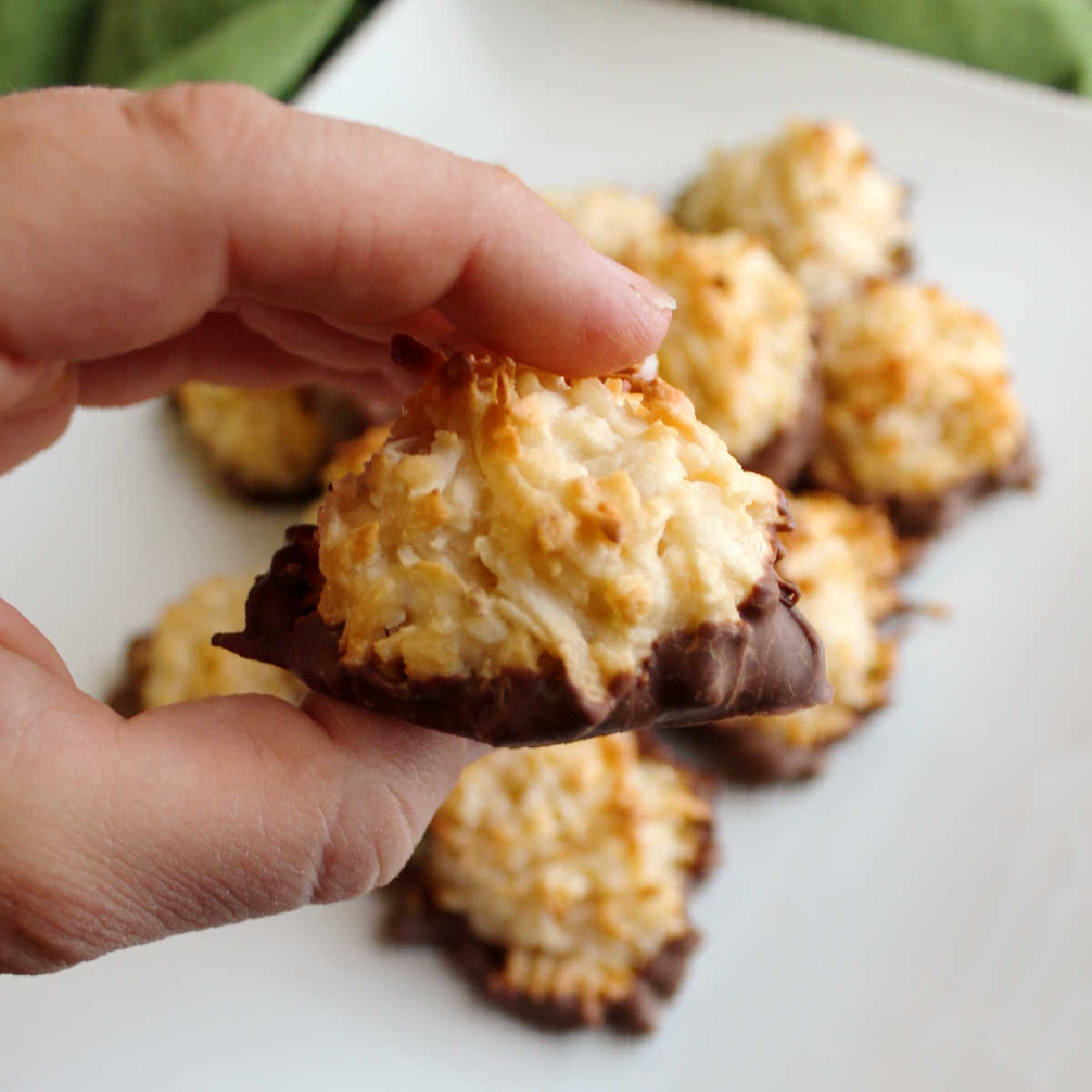 hand holding chocolate dipped coconut macaroon.