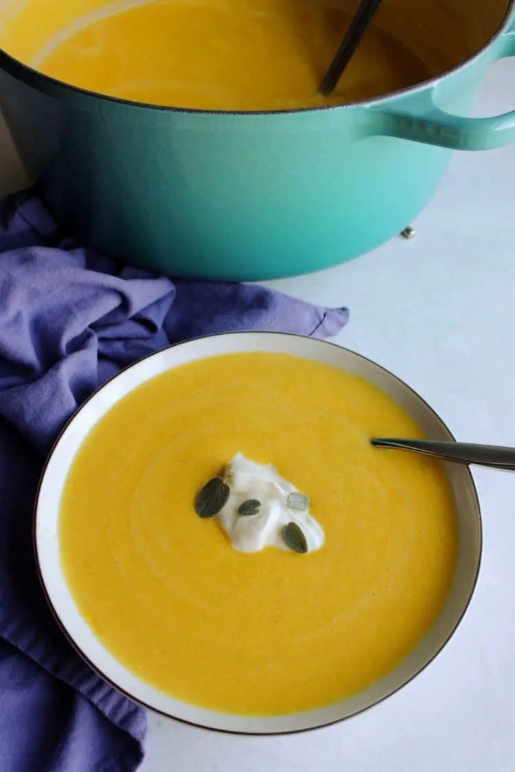bowl of pumpkin soup with yogurt and sage leaves.