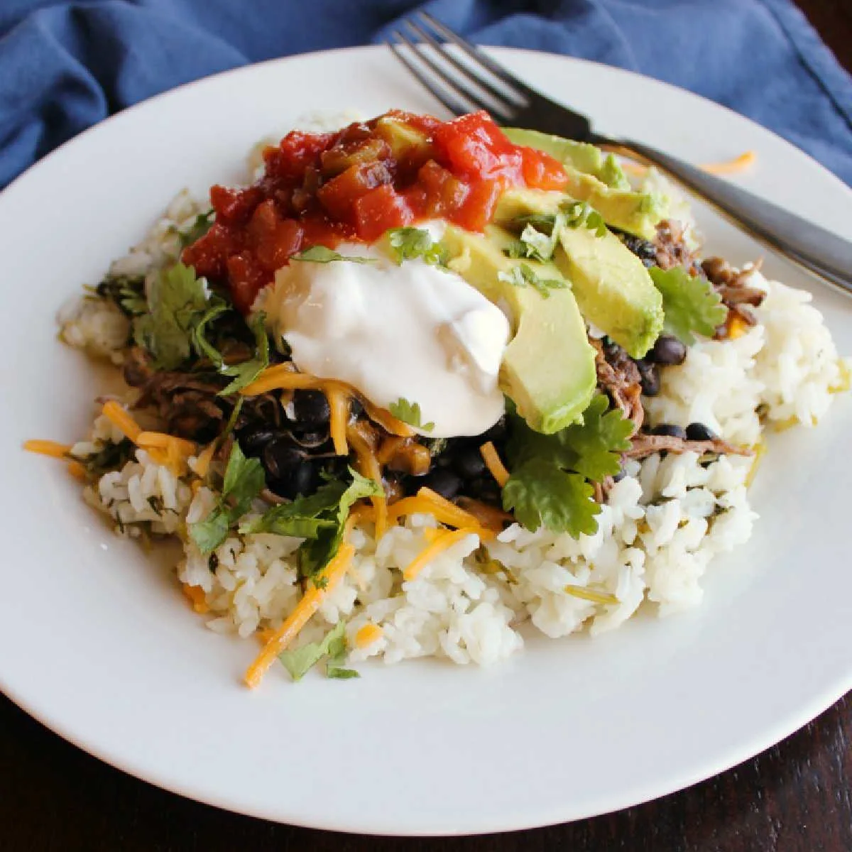 burrito bowl consisting of rice toped with salsa chicken, avocado, sour cream, salsa and more.
