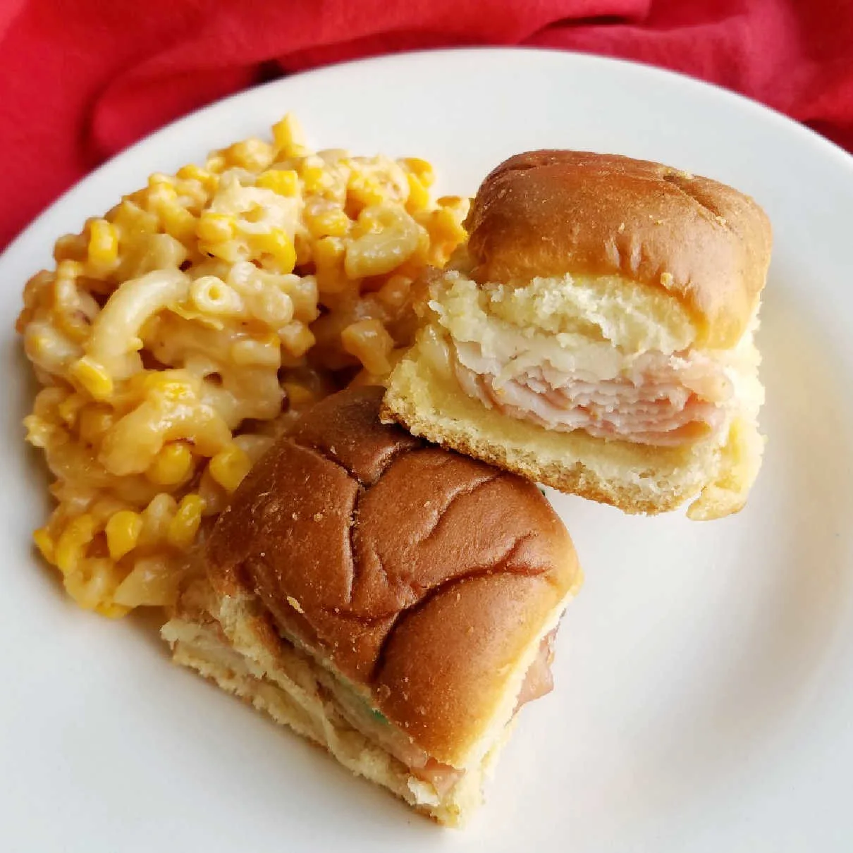 sliders on plate with macaroni and cheese and corn.