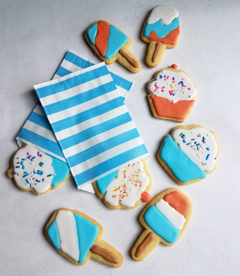 Sugar cookies cut into the shapes of popsicles and cupcakes decorated with red white and blue royal icing.